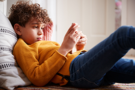 Boy lying down looks at a phone close up